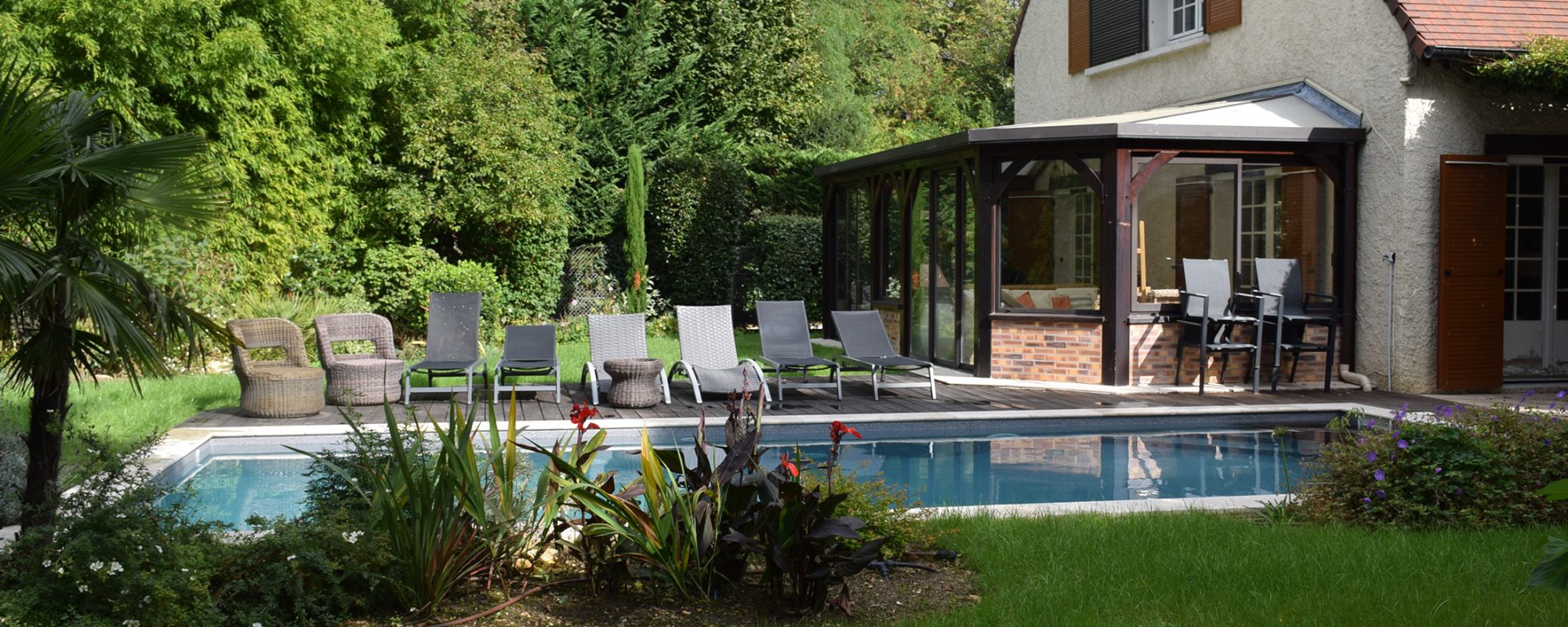 Piscine rectangulaire 9x4 avec volet motorisé , margelles en pierres naturelles avec une terrasse en bois