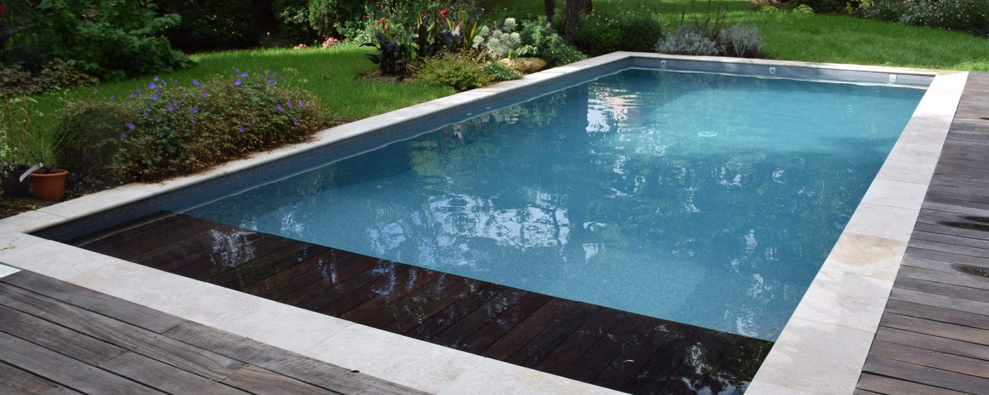 Piscine rectangulaire 9x4 avec volet motorisé , margelles en pierres naturelles avec une terrasse en bois